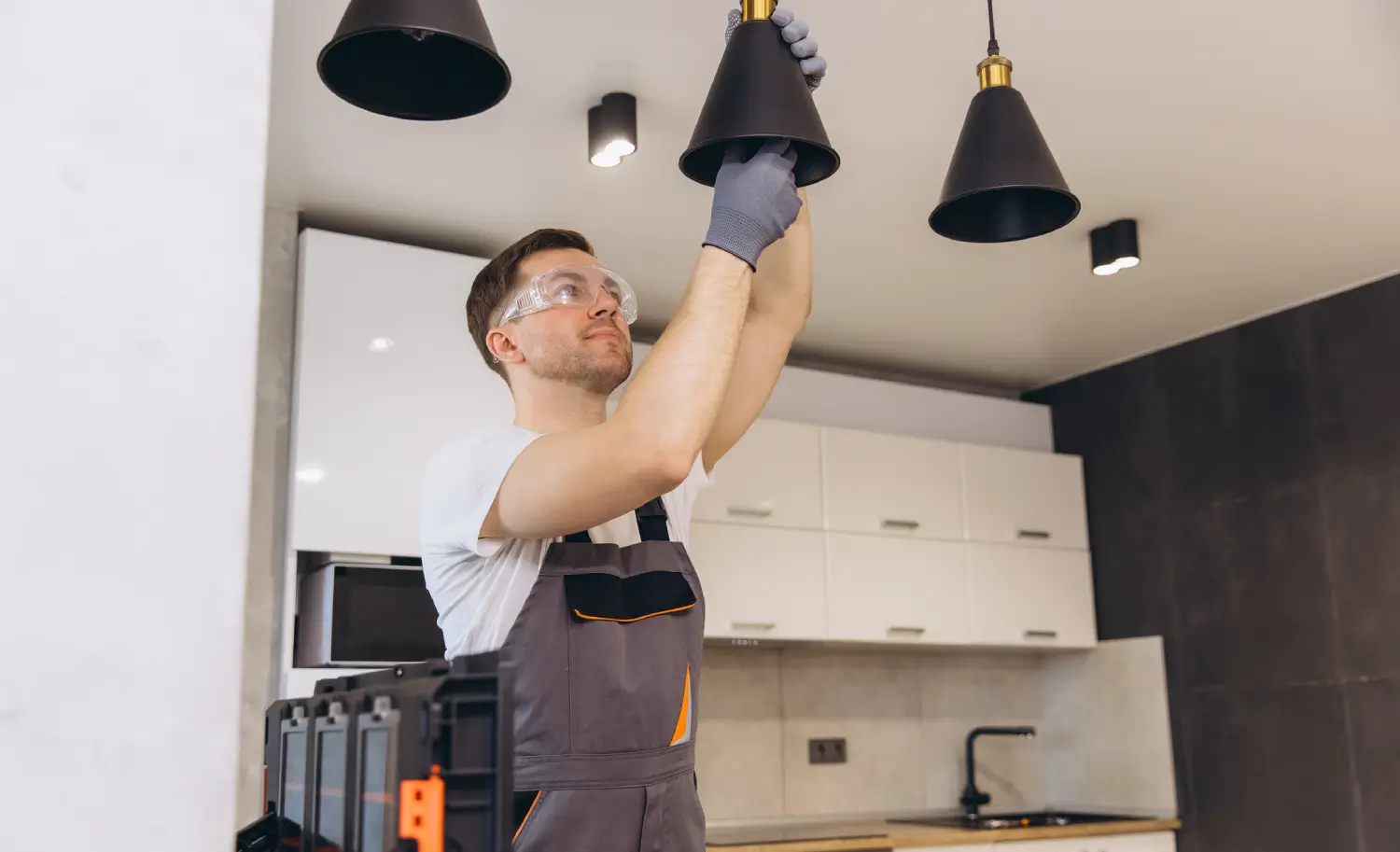 Electrician installing pendant lighting in modern kitchen